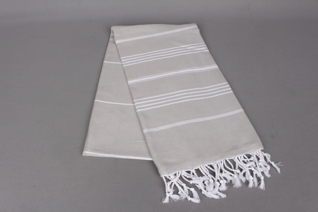 Gray  lightweight hamam towel with white stripes and fringes on a gray background
