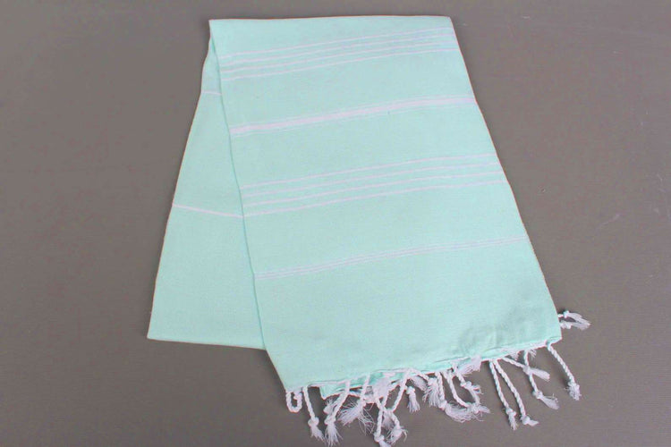 Mint lightweight hamam towel with white stripes and fringes on a gray background