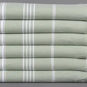 Stack of green and white striped lightweight hamam towels on a gray background