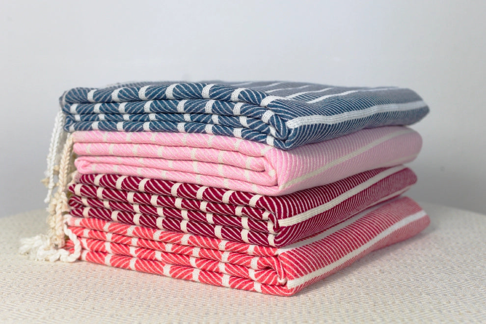 Stack of folded towels in blue, pink, and red with white patterns on a light background